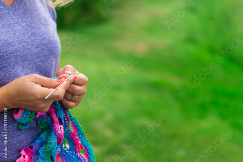 Craftswoman's hands knitting shawl with crochet