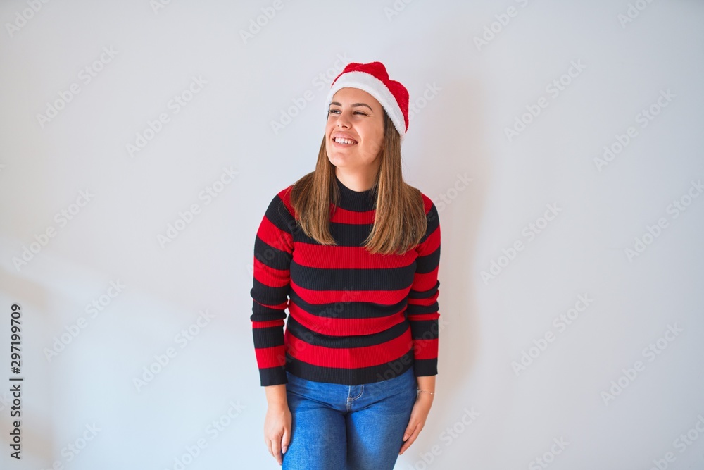 Young beautiful woman smilling happy wearing striped sweater and a santa claus hat at christmas Young beautiful woman smilling happy wearing striped sweater and a santa claus hat at christmas