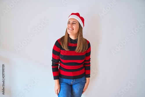 Young beautiful woman smilling happy wearing striped sweater and a santa claus hat at christmas © Krakenimages.com