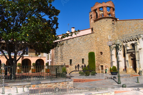 Main square in a charming medieval town in south of France. Stone wall, tower, arches and fruit tree at the background. Sunny summer day in Europe. photo