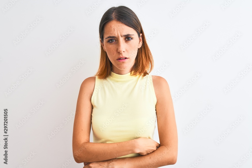 Beautiful redhead woman wearing yellow summer t-shirt over isolated background skeptic and nervous, disapproving expression on face with crossed arms. Negative person. Beautiful redhead woman wearing yellow summer t-shirt over isolated background skeptic and nervous, disapproving expression on face with crossed arms. Negative person.