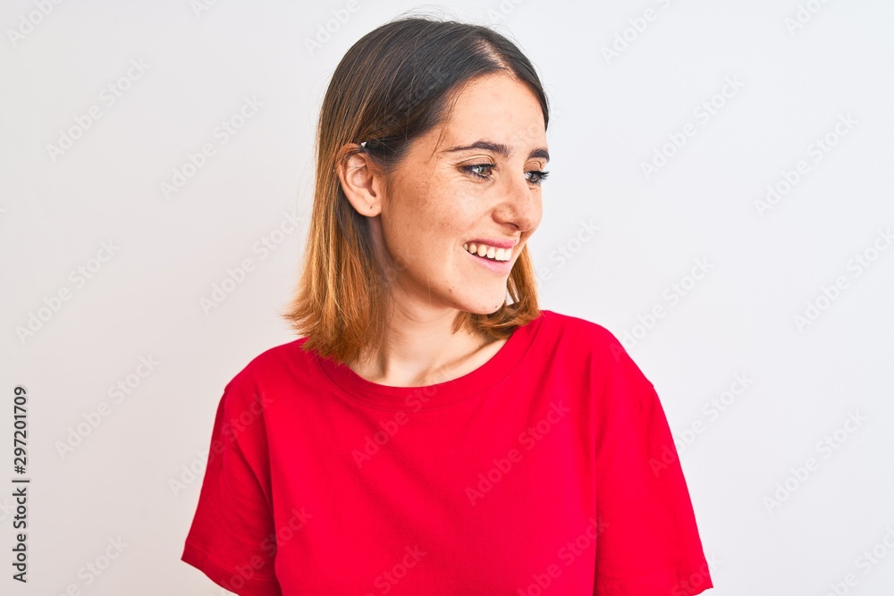 Beautiful redhead woman wearing casual red t-shirt over isolated background looking away to side with smile on face, natural expression. Laughing confident. Beautiful redhead woman wearing casual red t-shirt over isolated background looking away to side with smile on face, natural expression. Laughing confident.