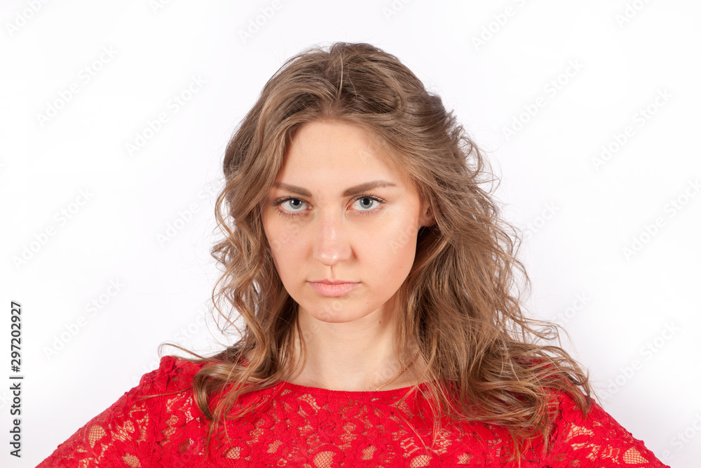 Curly young woman wearing a red dress looks appreciatively