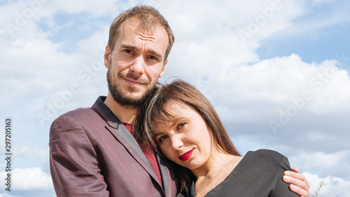A young loving couple are posing on the waterfront in a summer day.