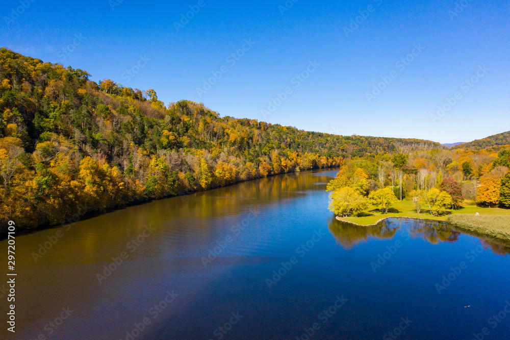 Autumn scene of colorful trees reflected in water with blue sky