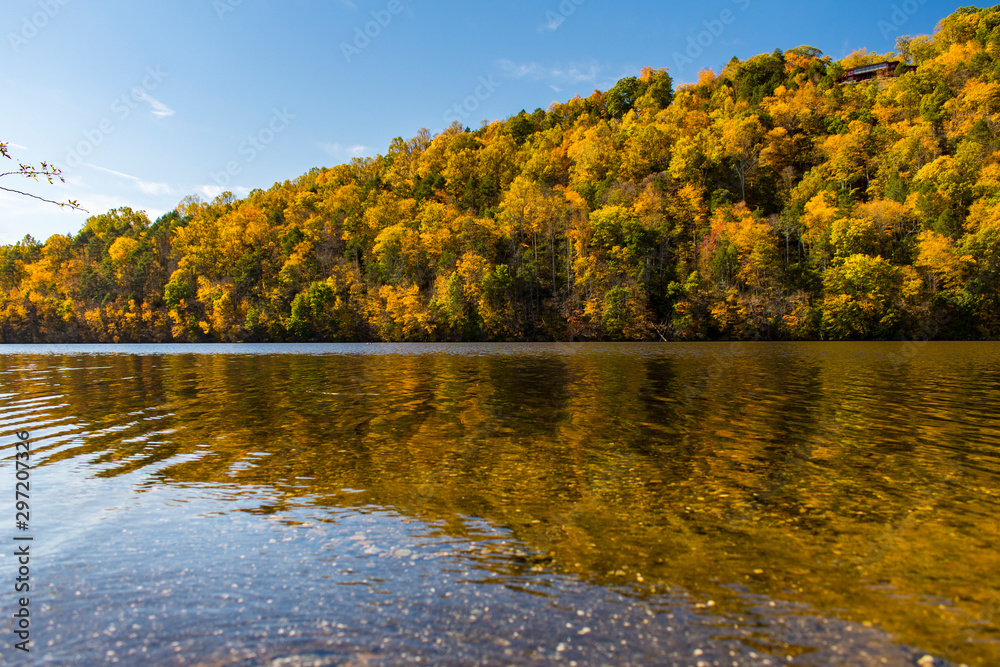 Autumn scene of colorful trees reflected in water with blue sky