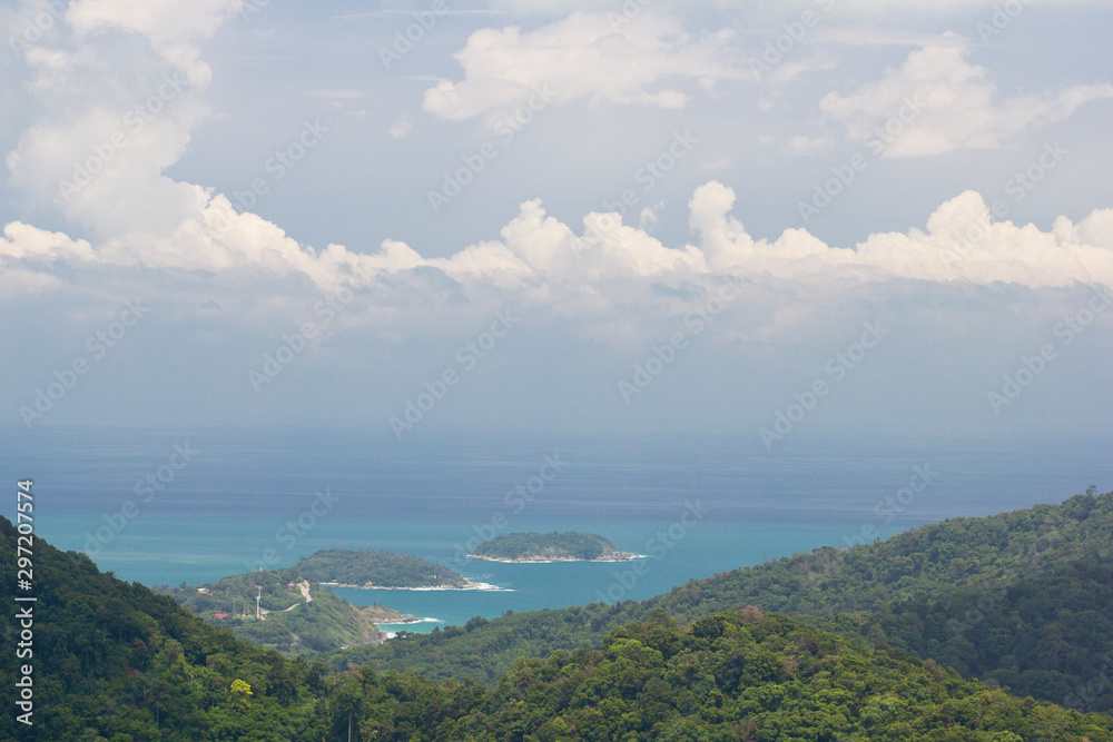 Tropical islands on the azure blue sea with cumulus clouds on a sunny day. Exotic round islands with green vegetation near the tropical sea coast. Rainforest on the shore of the turquoise sea.