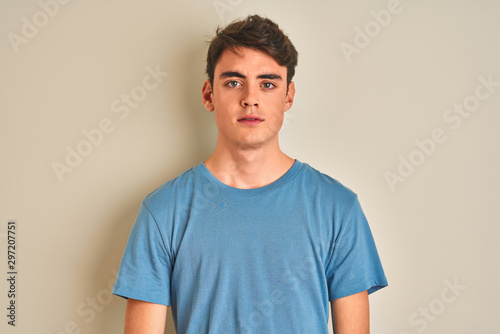 Teenager boy wearing casual t-shirt standing over isolated background with serious expression on face. Simple and natural looking at the camera.
