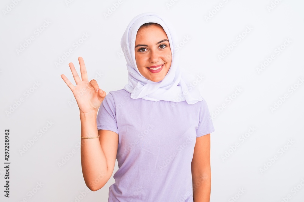 Young beautiful arabian girl wearing hijab standing over isolated white background smiling positive doing ok sign with hand and fingers. Successful expression.