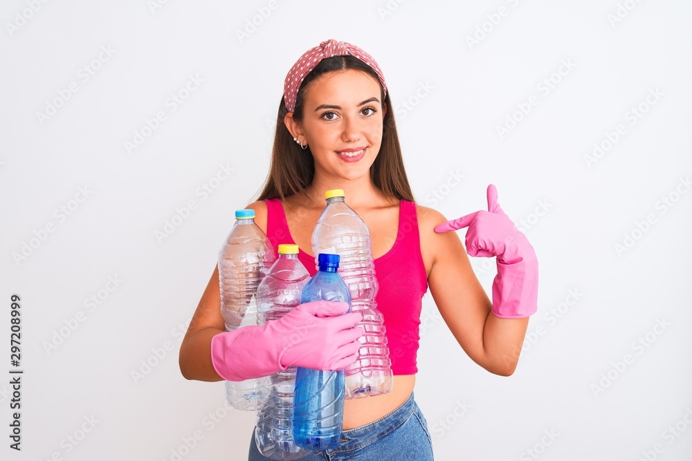 Beautiful girl wearing cleaner gloves recycling plastic bottles over isolated white background with surprise face pointing finger to himself Beautiful girl wearing cleaner gloves recycling plastic bottles over isolated white background with surprise face pointing finger to himself