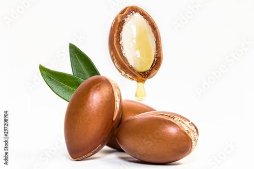 Argan nuts and oil on white background