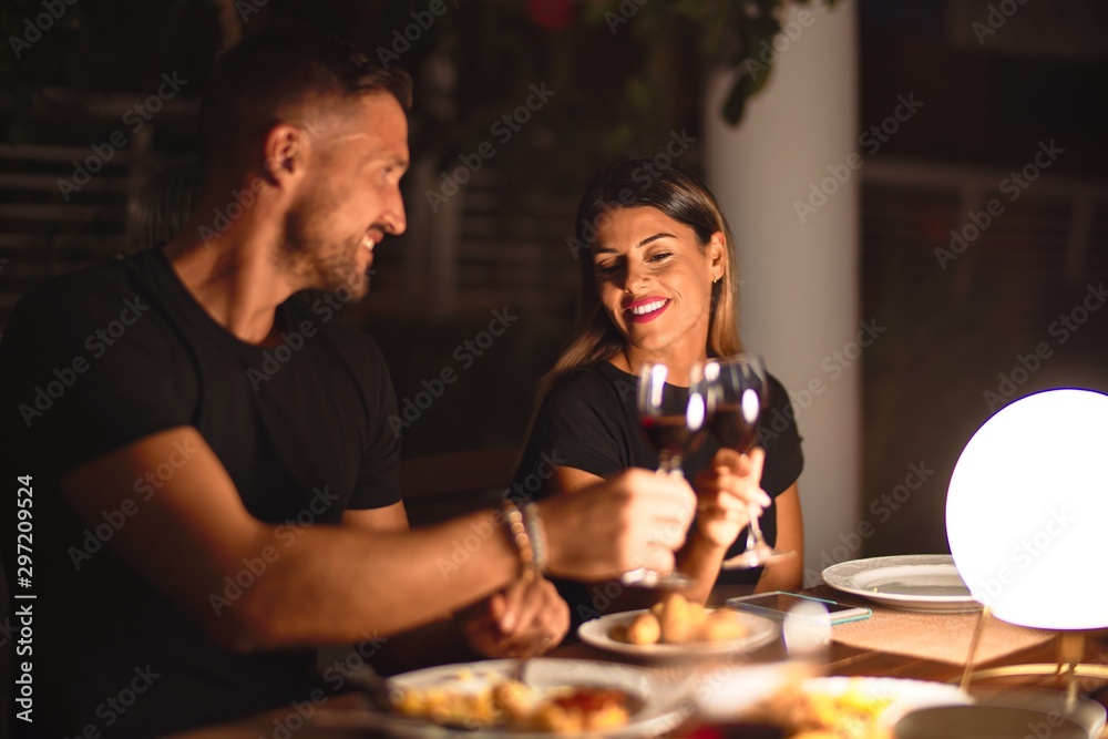 Young beautiful couple dinning on celebration toasting and smiling at terrace - obrazy, fototapety, plakaty 