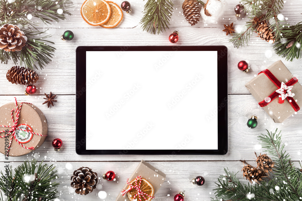 Creative layout frame made of Christmas tree branches, pine cones and  tablet pc on white wooden  background. Xmas and New Year theme. Flat lay, top view, space for text - obrazy, fototapety, plakaty 