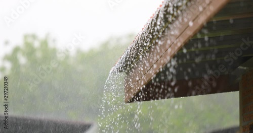 Rain flowing down from the roof house in rainy season