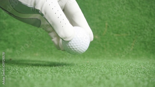 Golf ball and golfer's hand with glove on green grass