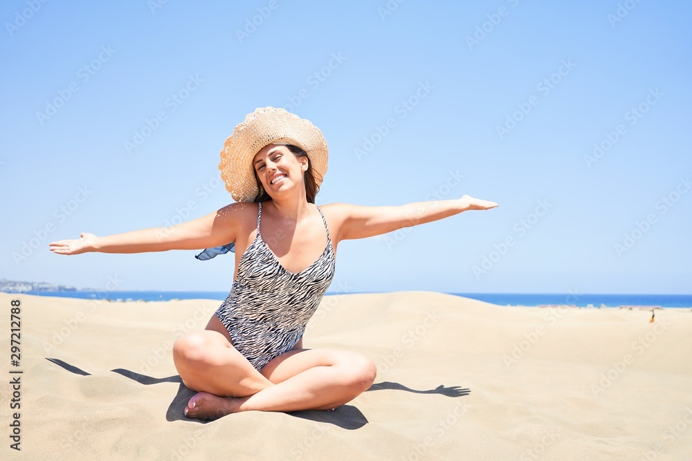Young beautiful woman sunbathing with open arms wearing summer swinsuit at maspalomas dunes bech Young beautiful woman sunbathing with open arms wearing summer swinsuit at maspalomas dunes bech