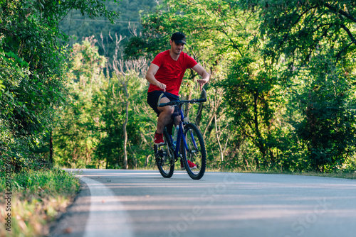 Happy biker cyclist riding his bike through the green woods.