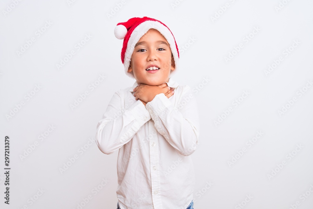 Beautiful kid boy wearing Christmas Santa hat standing over isolated white background shouting and suffocate because painful strangle. Health problem. Asphyxiate and suicide concept. Beautiful kid boy wearing Christmas Santa hat standing over isolated white background shouting and suffocate because painful strangle. Health problem. Asphyxiate and suicide concept.