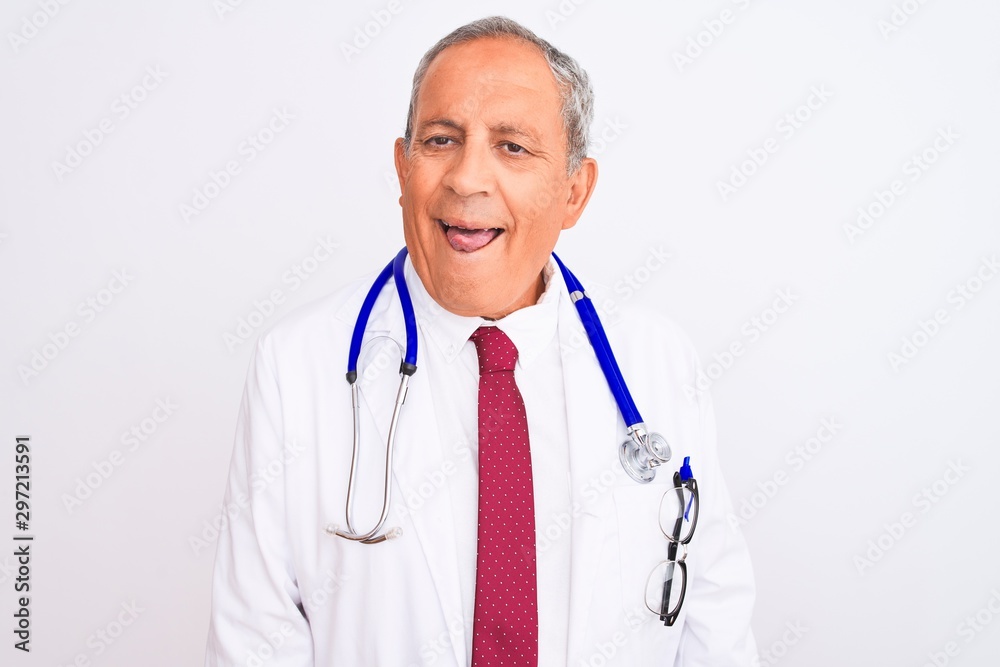 Senior grey-haired doctor man wearing stethoscope standing over isolated white background sticking tongue out happy with funny expression. Emotion concept. Senior grey-haired doctor man wearing stethoscope standing over isolated white background sticking tongue out happy with funny expression. Emotion concept.