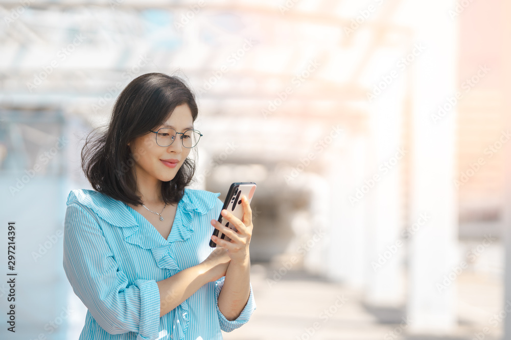 Young woman using smartphone under harsh sun light Young woman using smartphone under harsh sun light