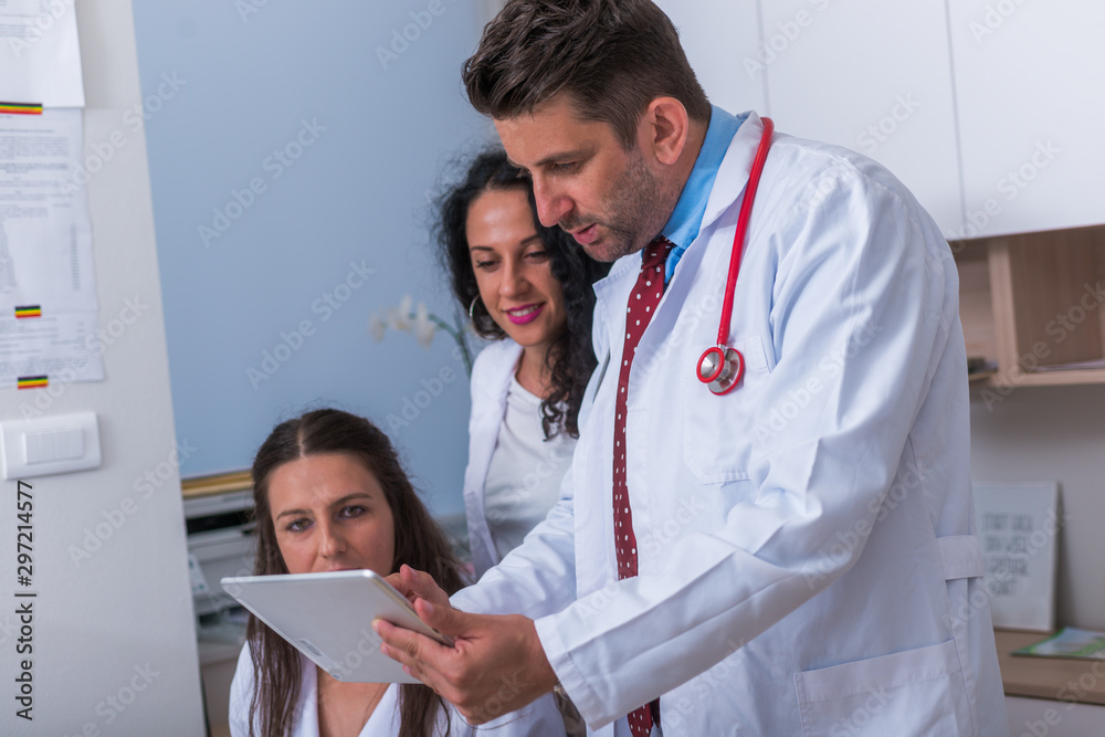 Two Physicians Two nurses ( female physicians ) and a male doctor looking in a tablet ...