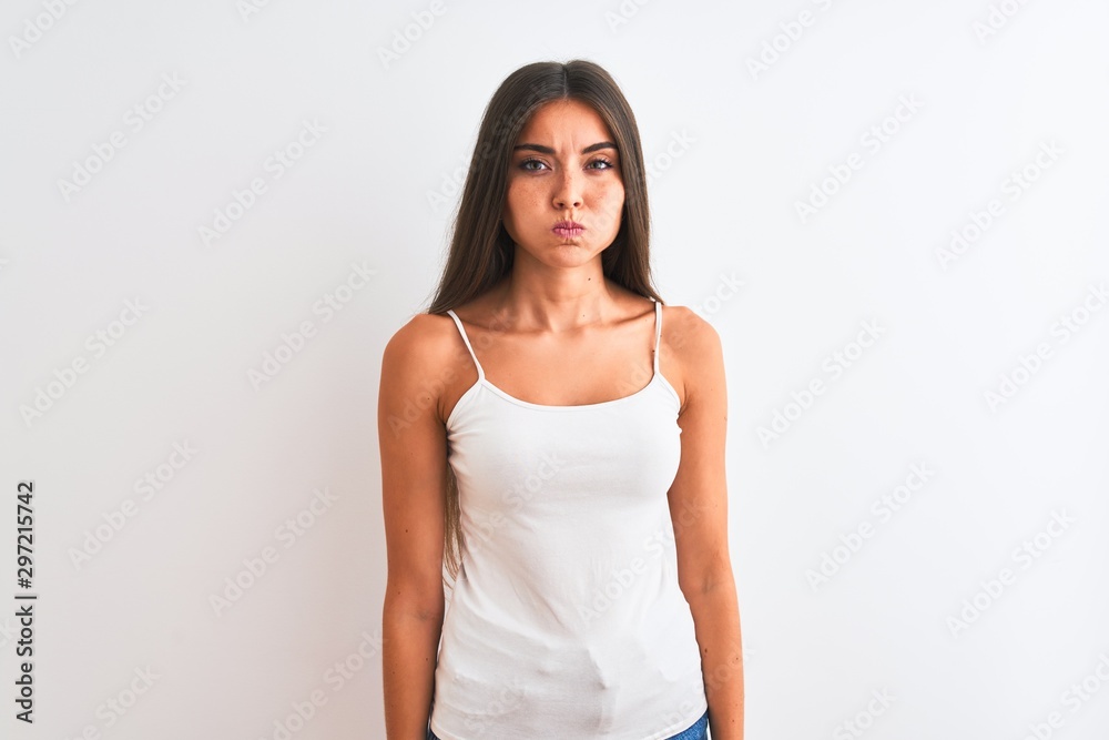 Young beautiful woman wearing casual t-shirt standing over isolated white background puffing cheeks with funny face. Mouth inflated with air, crazy expression. Young beautiful woman wearing casual t-shirt standing over isolated white background puffing cheeks with funny face. Mouth inflated with air, crazy expression.