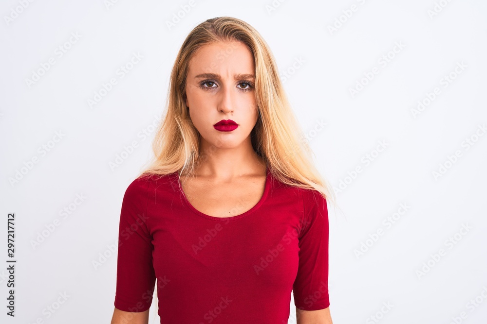 Young beautiful woman wearing red t-shirt standing over isolated white background skeptic and nervous, frowning upset because of problem. Negative person. Young beautiful woman wearing red t-shirt standing over isolated white background skeptic and nervous, frowning upset because of problem. Negative person.
