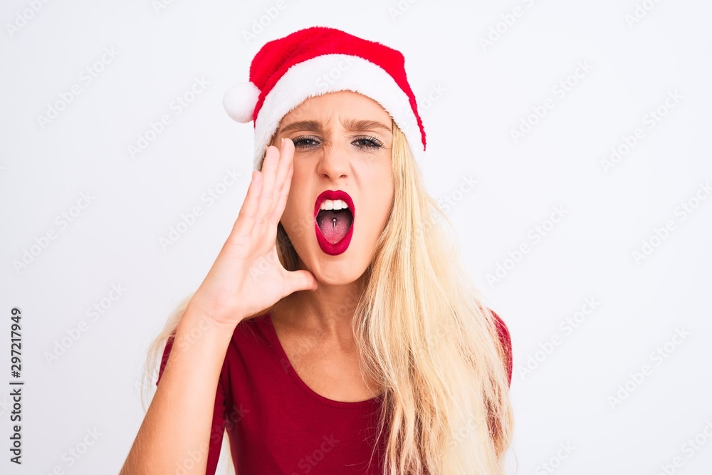 Young beautiful woman wearing Christmas Santa hat over isolated white background shouting and screaming loud to side with hand on mouth. Communication concept. Young beautiful woman wearing Christmas Santa hat over isolated white background shouting and screaming loud to side with hand on mouth. Communication concept.