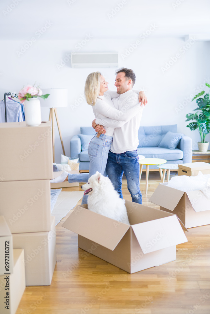 Young beautiful couple with dog hugging at new home around cardboard boxes Young beautiful couple with dog hugging at new home around cardboard boxes