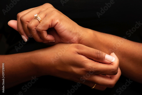 Isolated close-up of ethnic hands scratching on black background