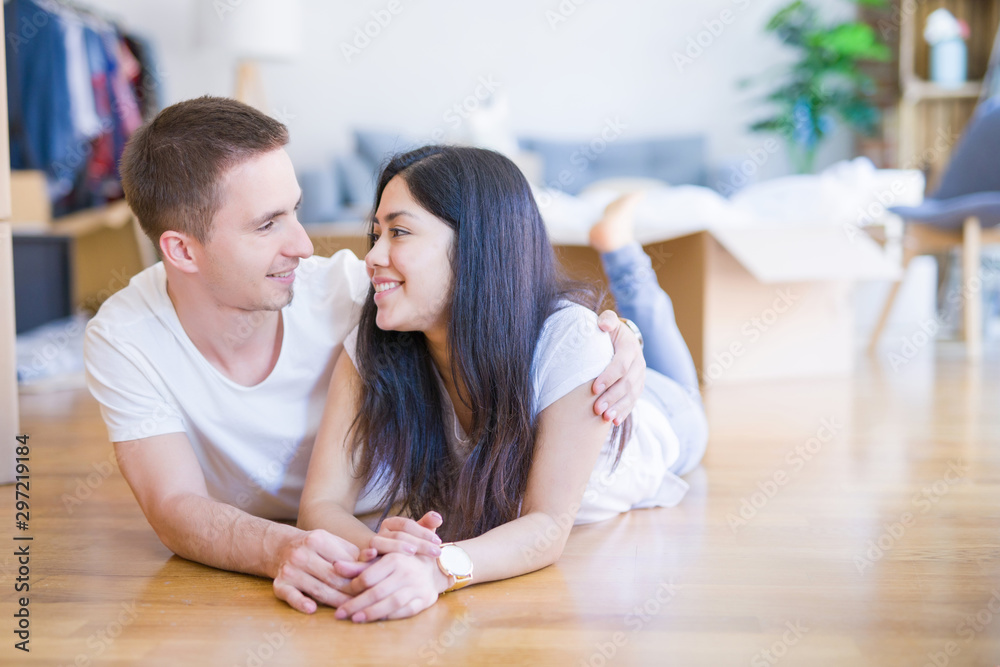 Young beautiful couple lying down at new home around cardboard boxes Young beautiful couple lying down at new home around cardboard boxes