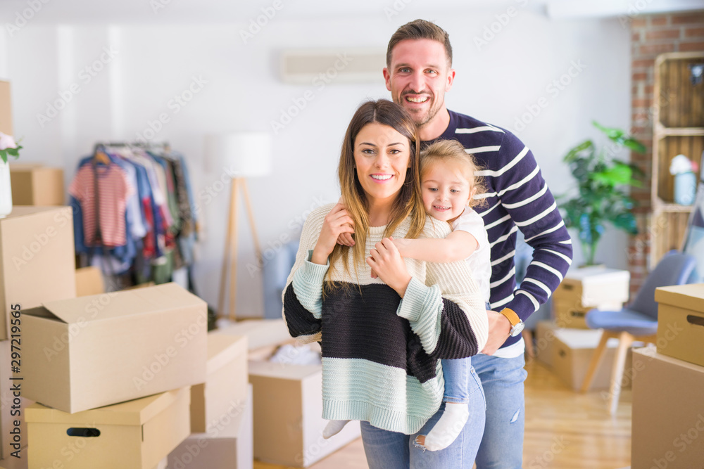 Beautiful family with a kid standing at new home around cardboard boxes