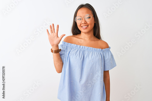 Young chinese woman wearing blue t-shirt and glasses over isolated white background showing and pointing up with fingers number five while smiling confident and happy.