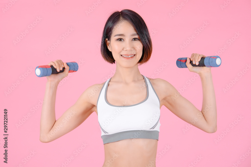 sport woman standing doing exercise for arms with dumbbells and showing muscle bodybuilding on pink backgrounds, fitness concept, sport concept sport woman standing doing exercise for arms with dumbbells and showing muscle bodybuilding on pink backgrounds, fitness concept, sport concept
