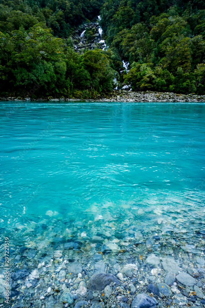 New Zealand tourism glacial blue river with waterfall New Zealand tourism glacial blue river with waterfall