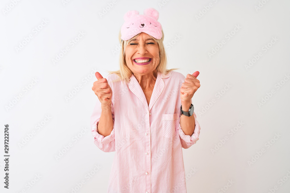Middle age woman wearing sleep mask and pajama over isolated white background excited for success with arms raised and eyes closed celebrating victory smiling. Winner concept. Middle age woman wearing sleep mask and pajama over isolated white background excited for success with arms raised and eyes closed celebrating victory smiling. Winner concept.