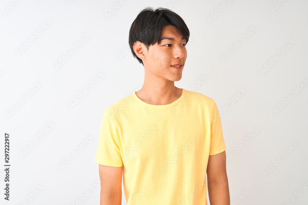 Chinese man wearing yellow casual t-shirt standing over isolated white background looking away to side with smile on face, natural expression. Laughing confident. Chinese man wearing yellow casual t-shirt standing over isolated white background looking away to side with smile on face, natural expression. Laughing confident.