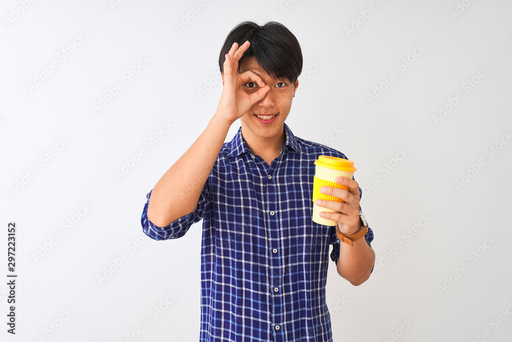 Young chinese man drinking take away coffee standing over isolated white background with happy face smiling doing ok sign with hand on eye looking through fingers Young chinese man drinking take away coffee standing over isolated white background with happy face smiling doing ok sign with hand on eye looking through fingers