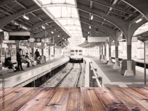 Wood table top over abstract blur background of train arriving at platform in Japan