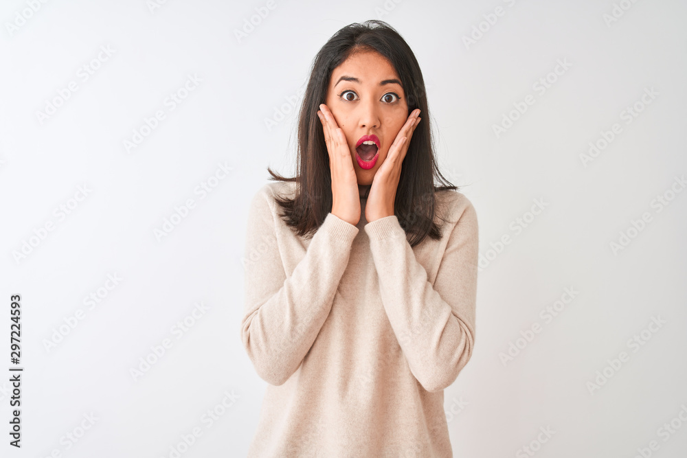 Beautiful chinese woman wearing turtleneck sweater standing over isolated white background afraid and shocked, surprise and amazed expression with hands on face