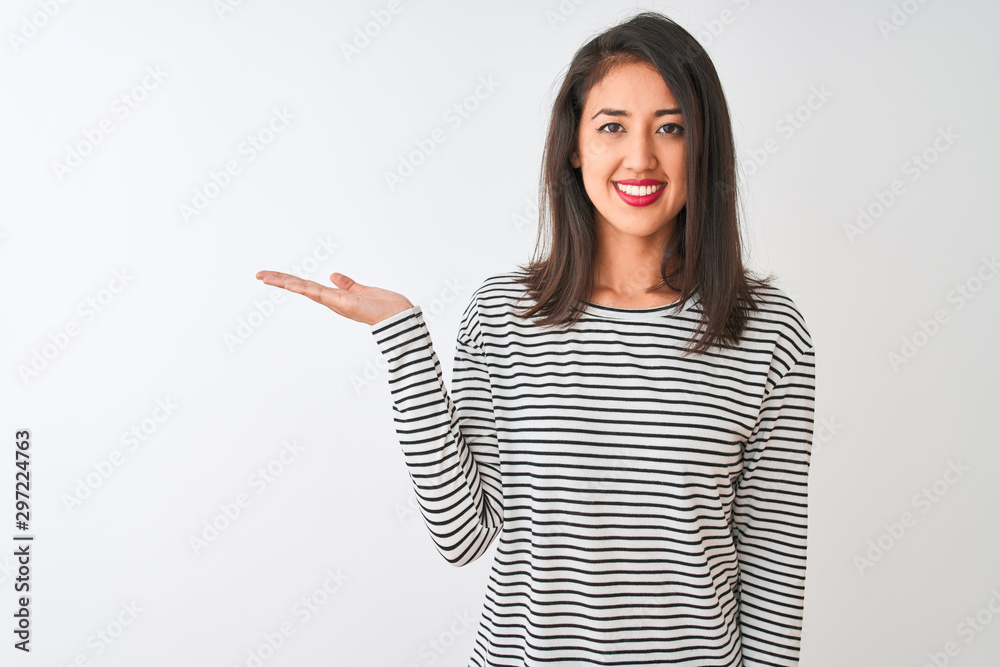 Young beautiful chinese woman wearing striped t-shirt standing over isolated white background smiling cheerful presenting and pointing with palm of hand looking at the camera. Young beautiful chinese woman wearing striped t-shirt standing over isolated white background smiling cheerful presenting and pointing with palm of hand looking at the camera.