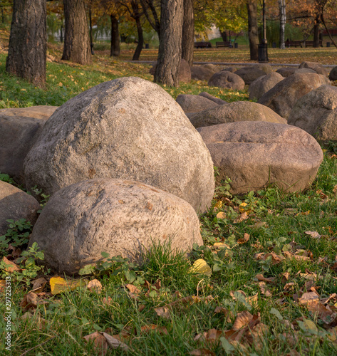 large stones and boulders with fallen leaves around in city part during autumn. nature, seasonal