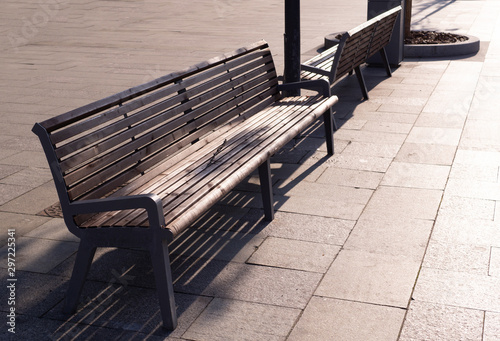 brown wooden bench on the street at sunset. furniture, city.