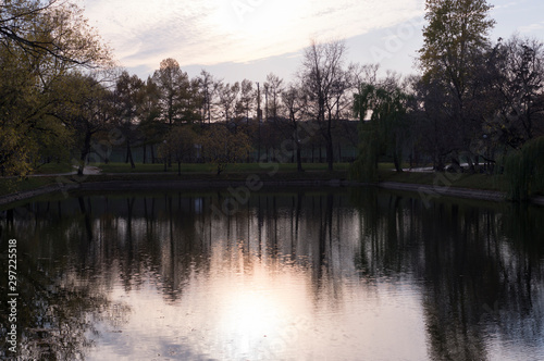 lake with reflections and fallen leaves at sunset in city park during autumn. nature, seasonal