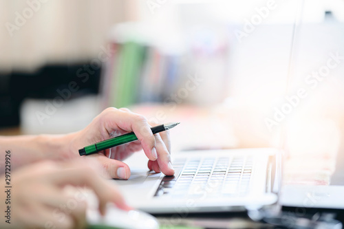 Closeup man hand holding pen and using laptop.