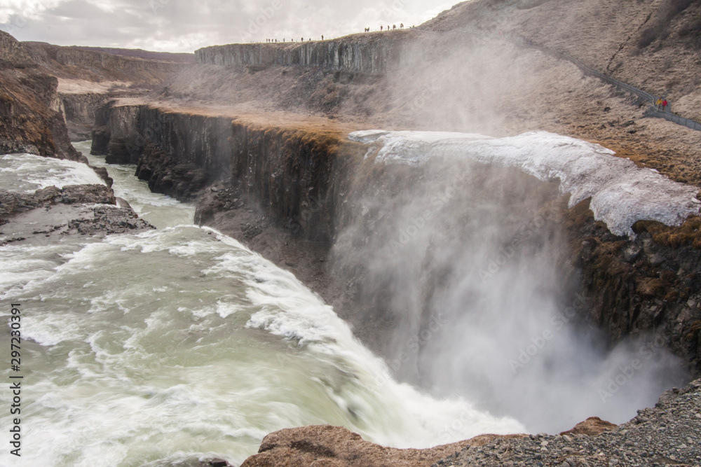 A three-step staircase of the Gullfoss waterfall on Hvita river, as pictured in detail (water plunging into the canyon, mossy cliffs, thick spray, panorama of the rapids)