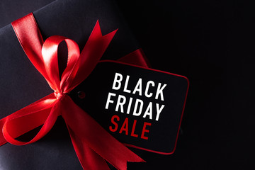 Top view of black christmas boxes with red paper tag on black background with copy space for text. black Friday composition.