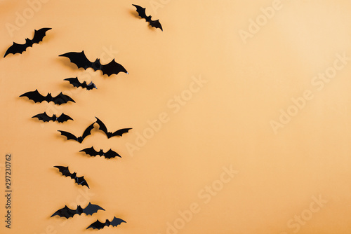 Top view of Halloween crafts, black paper bats flying over orange background with copy space for text. halloween concept. © Siam