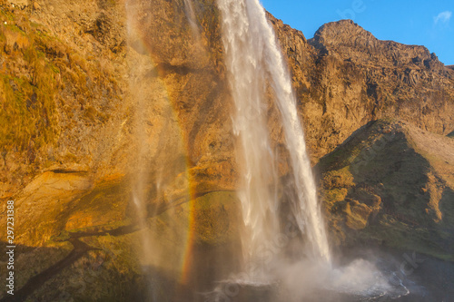 Waterfall Seljalandsfoss  part of Seljalands river taking its origin in Eyjafjallaj  kull volcano glacier  in southern Iceland  captured during sunset hour with a rainbow