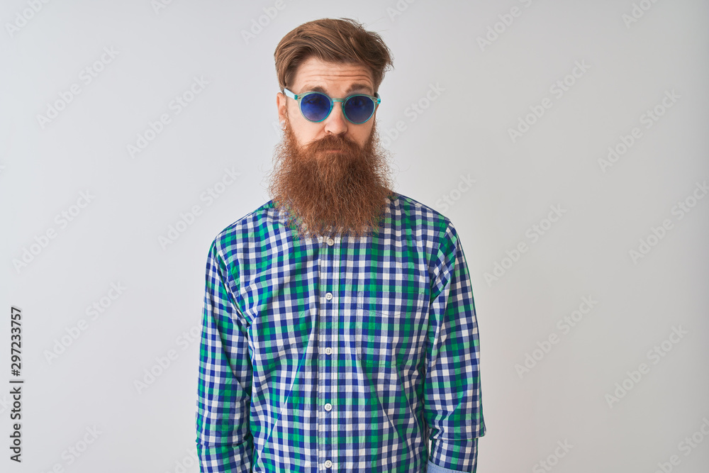 Young redhead irish man wearing casual shirt and sunglasses over isolated white background skeptic and nervous, frowning upset because of problem. Negative person.